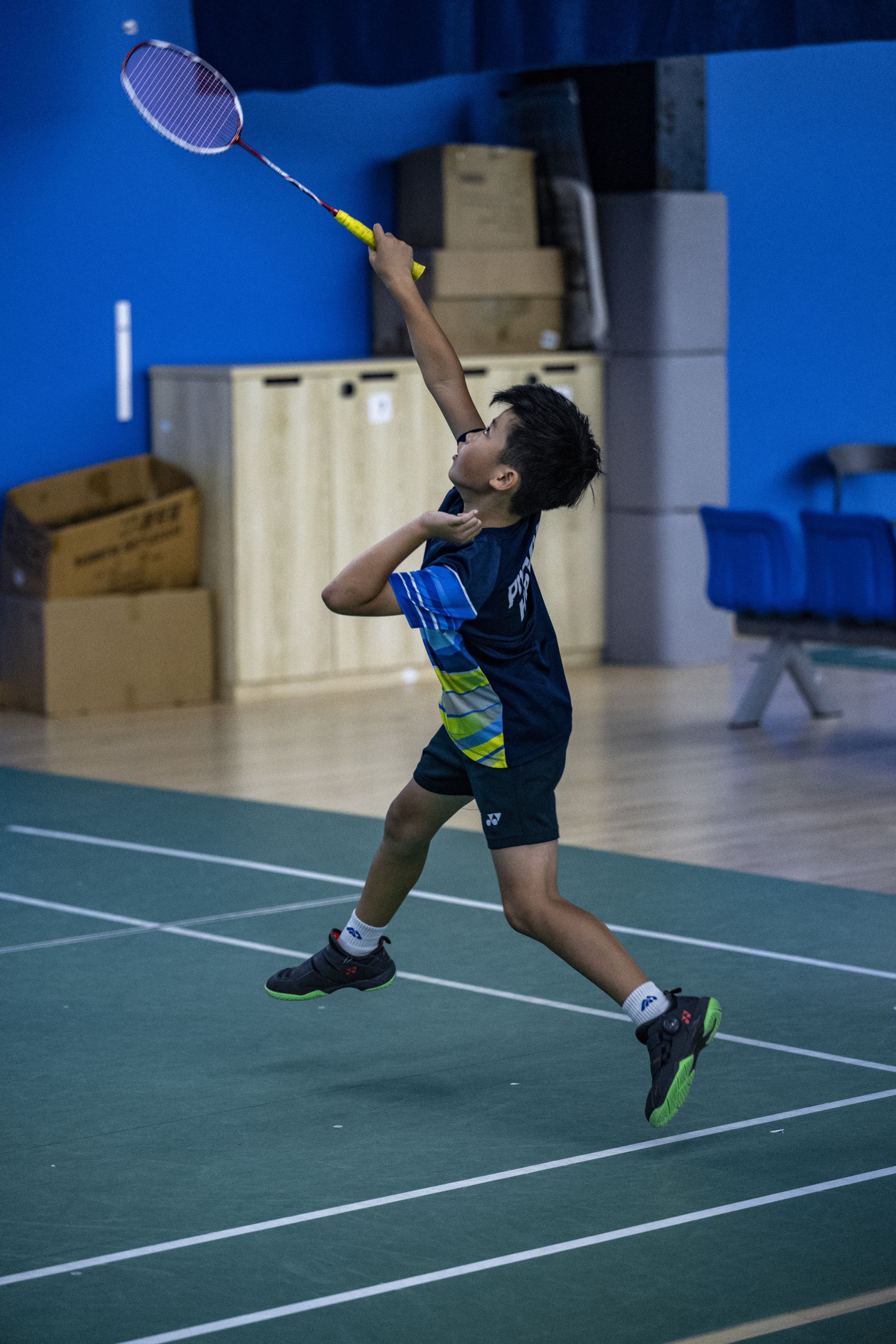 Young badminton player jumping to hit a shuttlecock